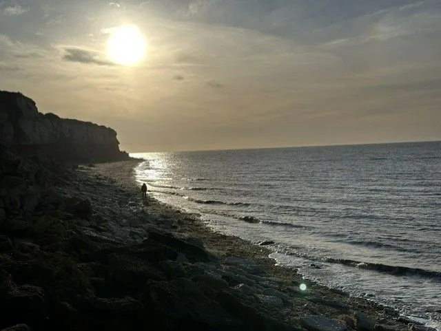 The striped cliffs at sunset with the low sun over the sea and chalk and red rock layers along the shore